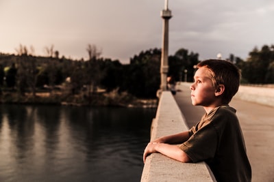 选择聚焦的照片的男孩在桥附近的水域
